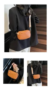 Detail van de bruine PU-lederen crossbodytas met brede schouderriem met golfpatroon en goud decor