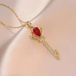 Macro shot of gold crown key pendant with red teardrop gem on satin fabric background