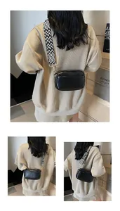 Detail van minimalistische zwarte lederen crossbodytas met een geometrische geweven riem