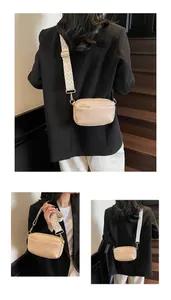 Detail van de crème mini crossbody tas met zwart-wit gedessineerde band en goudkleurige hardware