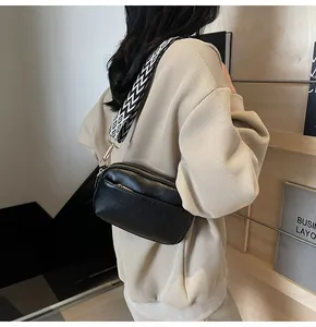 Detail van zwarte lederen crossbodytas met geometrische brede riem en gouden gespen