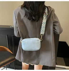 Detail van lichtblauwe crossbody tas met blauw-witte geometrische schouderband