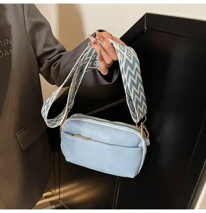 Detail van lichtblauwe vierkante crossbodytas met leertextuur en geweven schouderriem