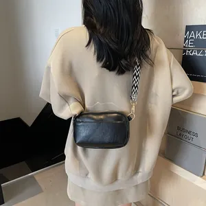 Modieuze zwarte crossbodytas met een opvallende brede schouderband met golfpatroon
