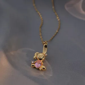 Golden rabbit pendant necklace with pink oval gemstone and crystal accents on silk background