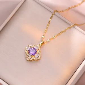 Dettaglio del ciondolo a fiore dorato con zircone viola e cristalli bianchi lucidi