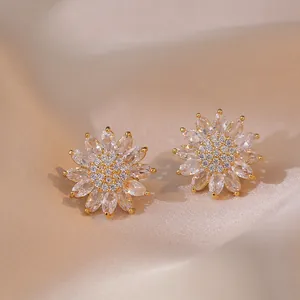 Boucles d'oreilles tournesol dorées avec cristaux de zircon sur fond de satin champagne