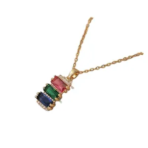 Macro shot of gold necklace with red green blue gems and zircon halo detail