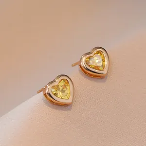 Eleganti orecchini a cuore in oro con zirconi gialli su tessuto morbido a coste