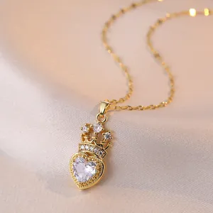 Collier élégant avec pendentif cœur doré et couronne d'émeraude sur fond de soie douce
