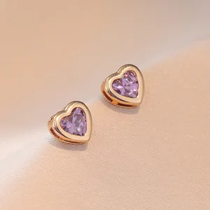 Élégantes boucles d'oreilles cœur en or avec zircons violets facettés sur tissu beige