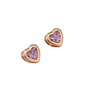 Boucles d'oreilles cœur en or rose avec zircons roses sur fond blanc pur