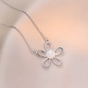 Dettaglio macro del ciondolo a fiore in argento con petali di zircone su raso rosa morbido
