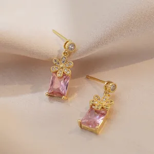 Pink rectangular gemstone earrings with gold floral accents and silk backdrop