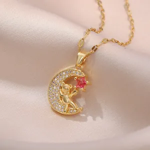 Collar de luna dorada con un pequeño oso y estrella rosa sobre fondo de seda suave