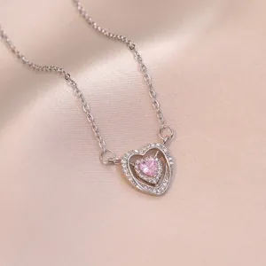 Pink heart pendant necklace with crystal accents on a luxurious pink silk background