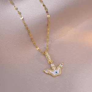 Golden crown evil eye necklace with white inlay and sparkling stones on a silk fabric