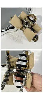 Detailed view of khaki and plaid fabric bow hair clip with smooth black spring clamp