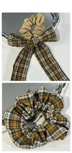 Detail view of yellow plaid bow scrunchies set on a textured white background surface