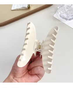 Dettaglio della molletta per capelli crema con meccanismo a molla e design a presa forte