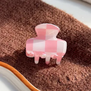 Close-up of pink and white checkered hair claw clip with glossy finish and high texture