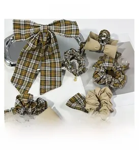 Detail view of plaid bow hair clip and matching scrunchies set on white background