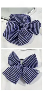 Détail d'un chouchou en maille rayé violet et noir avec son nœud assorti sur soie blanche