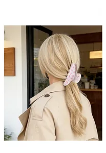 Detail einer großen Haarspange mit rosa Blumenmuster, getragen von blondem Model
