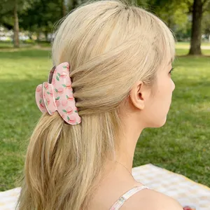 Pink hair claw clip with peach print shown on a model in a natural outdoor setting