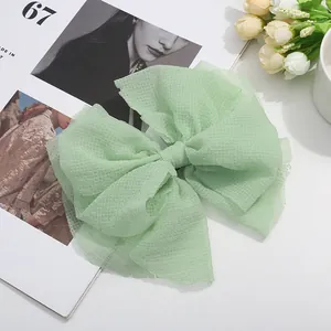 Macro d'une pince à cheveux en tulle vert menthe avec nœud multicouche texturé