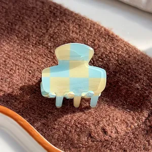 Detail of checkered hair claw clip in light blue and yellow with glossy acetate finish