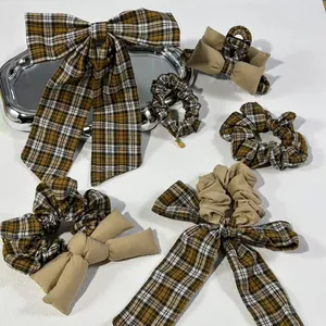 Elegant yellow plaid bow hair clip and scrunchies set on white textured surface