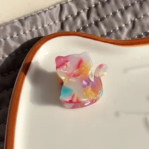 Detail of a small cat-shaped hair claw clip with colorful marble acetate texture
