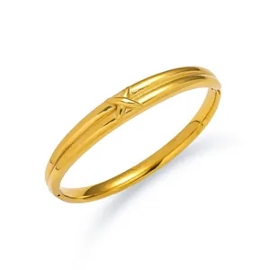 Detail of gold-plated Roman numeral bangle showing X-shaped relief and hinge mechanism