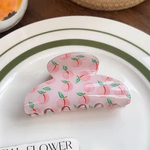 Close-up of pink peach print hair claw clip on white ceramic plate for summer styling