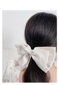 Detailansicht der großen weißen Satin-Schleife Haarspange auf dem Kopf des Models