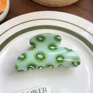 Close-up of mint green hair claw clip with realistic kiwi fruit print on a ceramic plate
