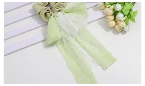 Detail of sweet green pleated fabric scrunchie with lace trim and elegant long ribbons