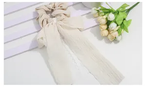 Detail of cream lace scrunchie with long ribbon streamers and floral decorative accents