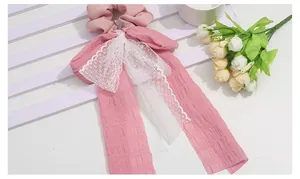 Detailed close-up of pink lace ribbon scrunchie with sweet floral and bow decoration