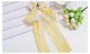 Detail of yellow lace bow hair scrunchie with long ribbons and pleated fabric texture