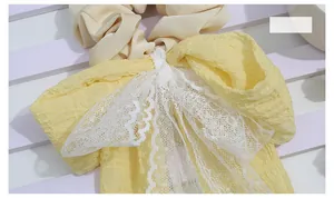 Macro view of bright yellow pleated hair scrunchie with white lace trim and bow detail