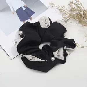 Close-up of a black satin scrunchie with floral mesh splice and delicate white pearls
