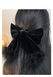 Detail of black velvet bow hair clip with feathers worn on dark hair for daily style