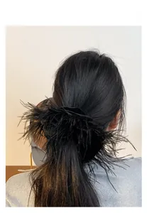 Detail of fluffy black feather scrunchie hair clip styled on a ponytail for women