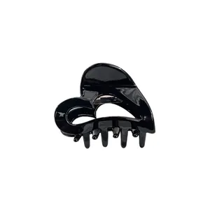 Glänzende schwarze herzförmige Haarklammer mit hohlem Design für Damen auf weißem Grund