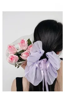 Détail d'une pince à cheveux à triple nœud en organza lavande avec rubans et paillettes