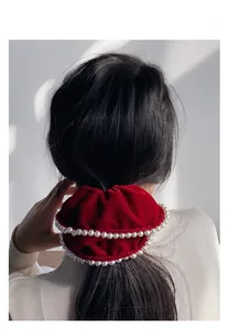 Detailed view of a red velvet oversized scrunchie with double row faux pearls