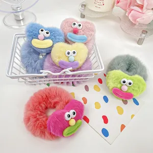 Chouchous pelucheux colorés avec motifs monstres mignons dans un panier décoratif