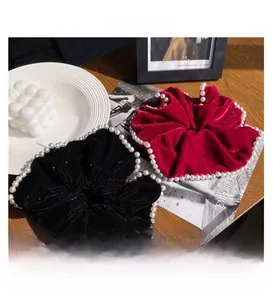 Detail of luxury velvet scrunchies in black and burgundy with elegant pearl trim decor
